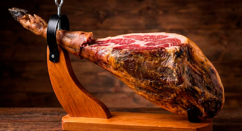 Jamón ibérico de bellota curado colocado en soporte jamonero listo para el corte