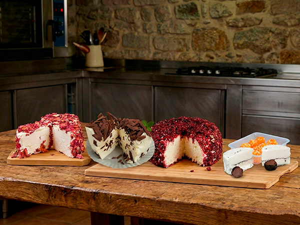 Tabla de quesos de diferentes tipos sobre mesa de madera en cocina rústica