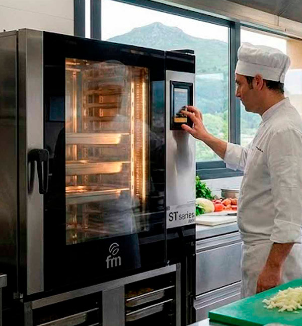 Chef profesional programando el panel táctil de un horno mixto FM Industrial ST Series en una cocina profesional en Asturias, ajustando los parámetros de cocción.