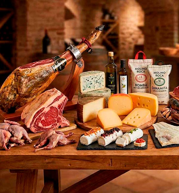 Bodegón de productos gourmet para hostelería con arroz Molino Roca, selección de quesos artesanos, carnes premium, jamón ibérico y aceites de oliva virgen extra.